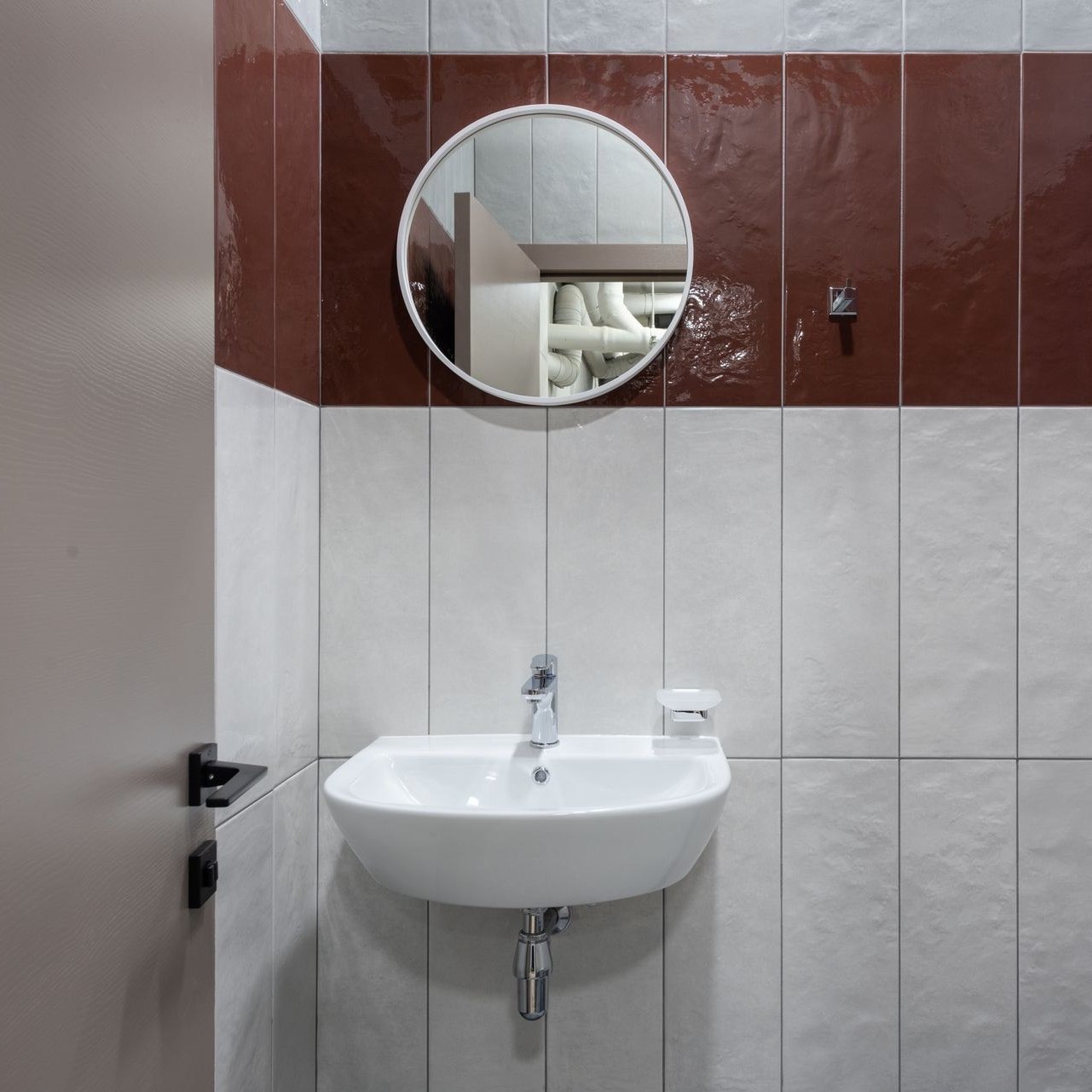 Compact tiled restroom with a white basin and round mirror
