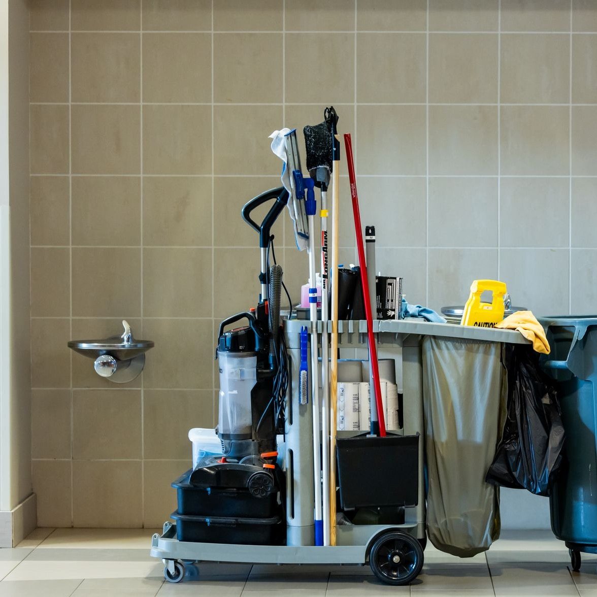 Fully stocked janitorial cart with mops, supplies, and a rolling bin