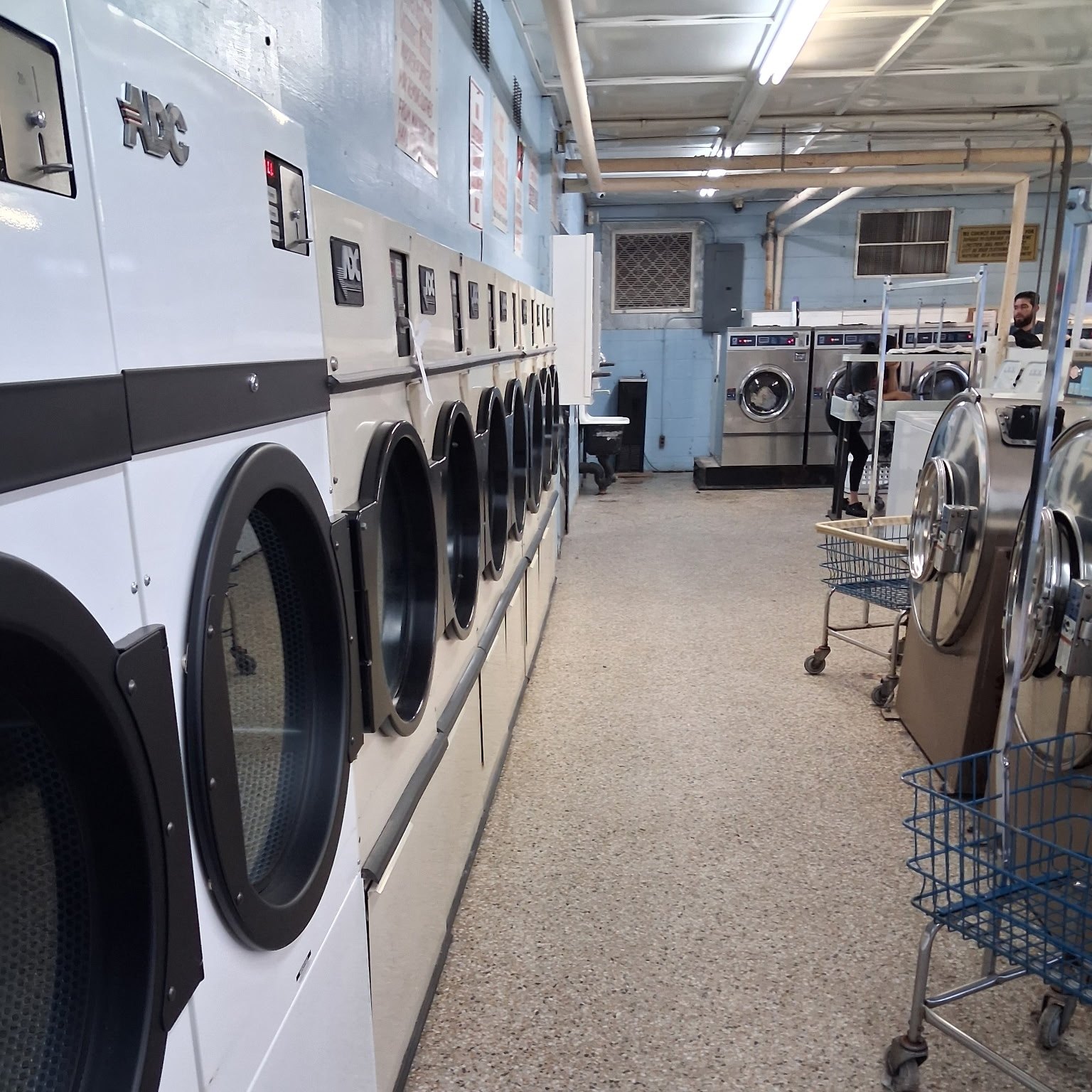 Shared laundry room after cleaning, with the floor mopped and carts returned to the wall