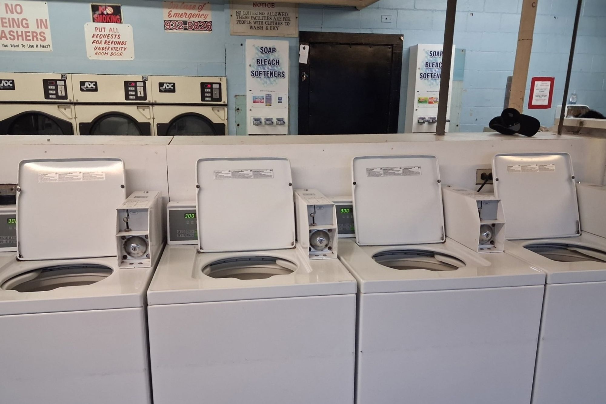Row of top-load washers wiped down in a shared laundry room