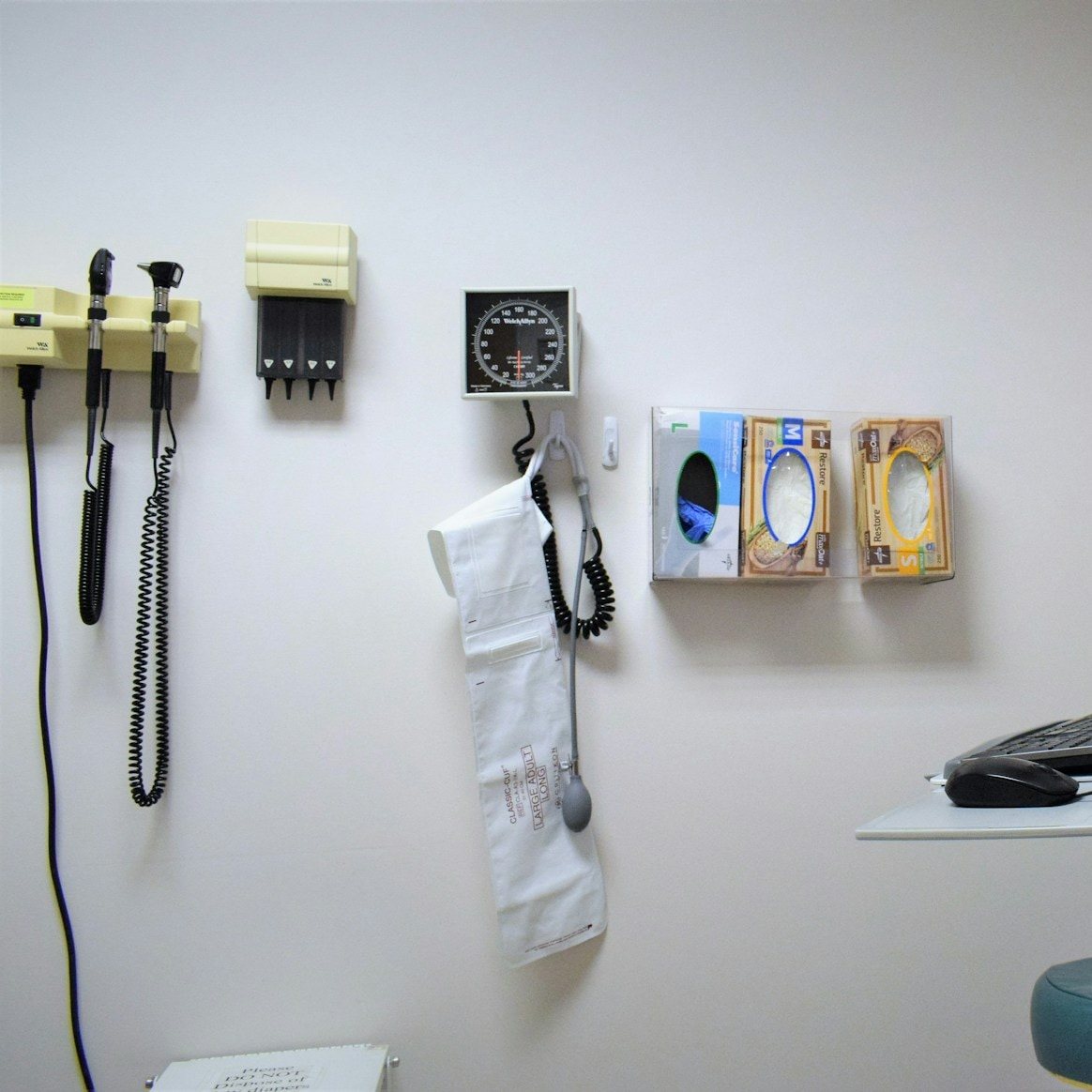 Exam room wall with diagnostic instruments and dispensers wiped down