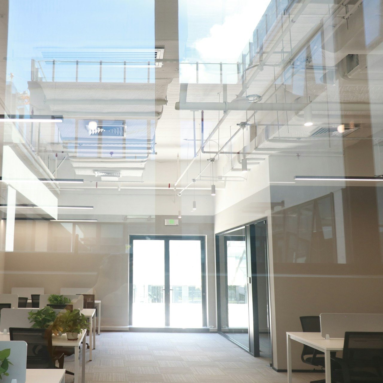 Bright open-plan office with white desks under a skylit atrium