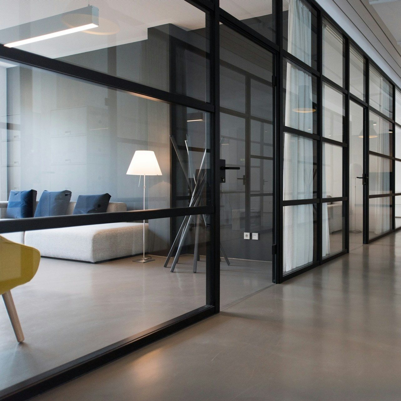 Office corridor with black-framed glass partitions and a lounge area