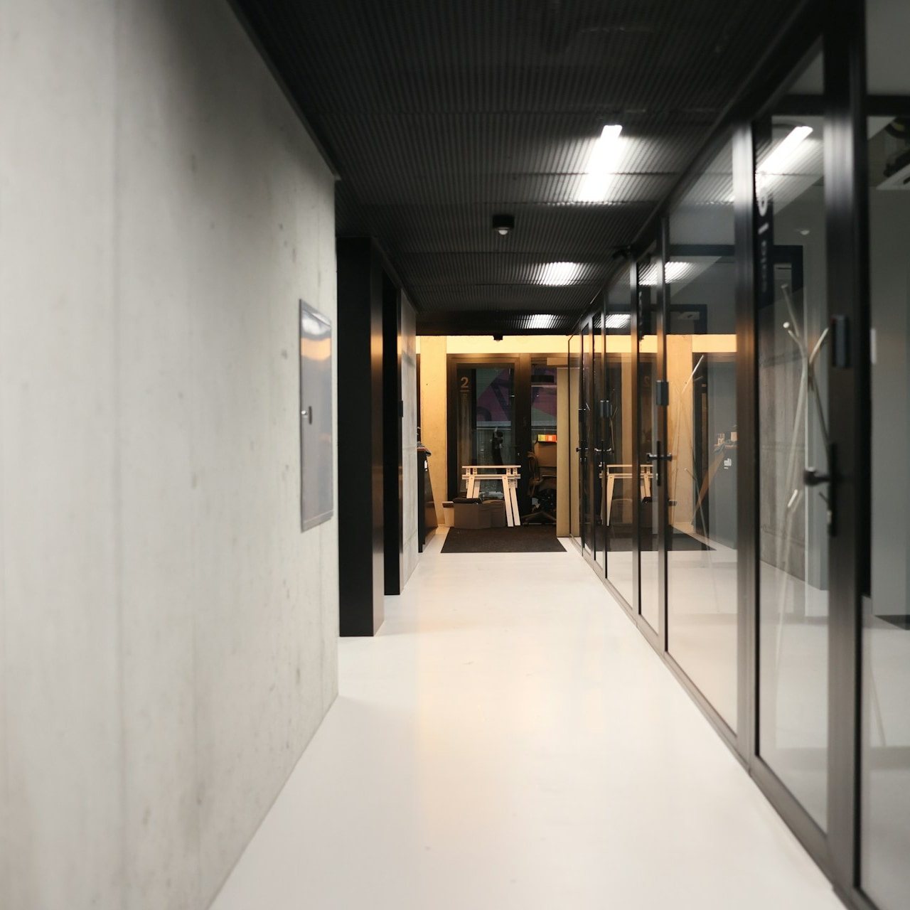 Office hallway with dark glass meeting pods and corkboard walls