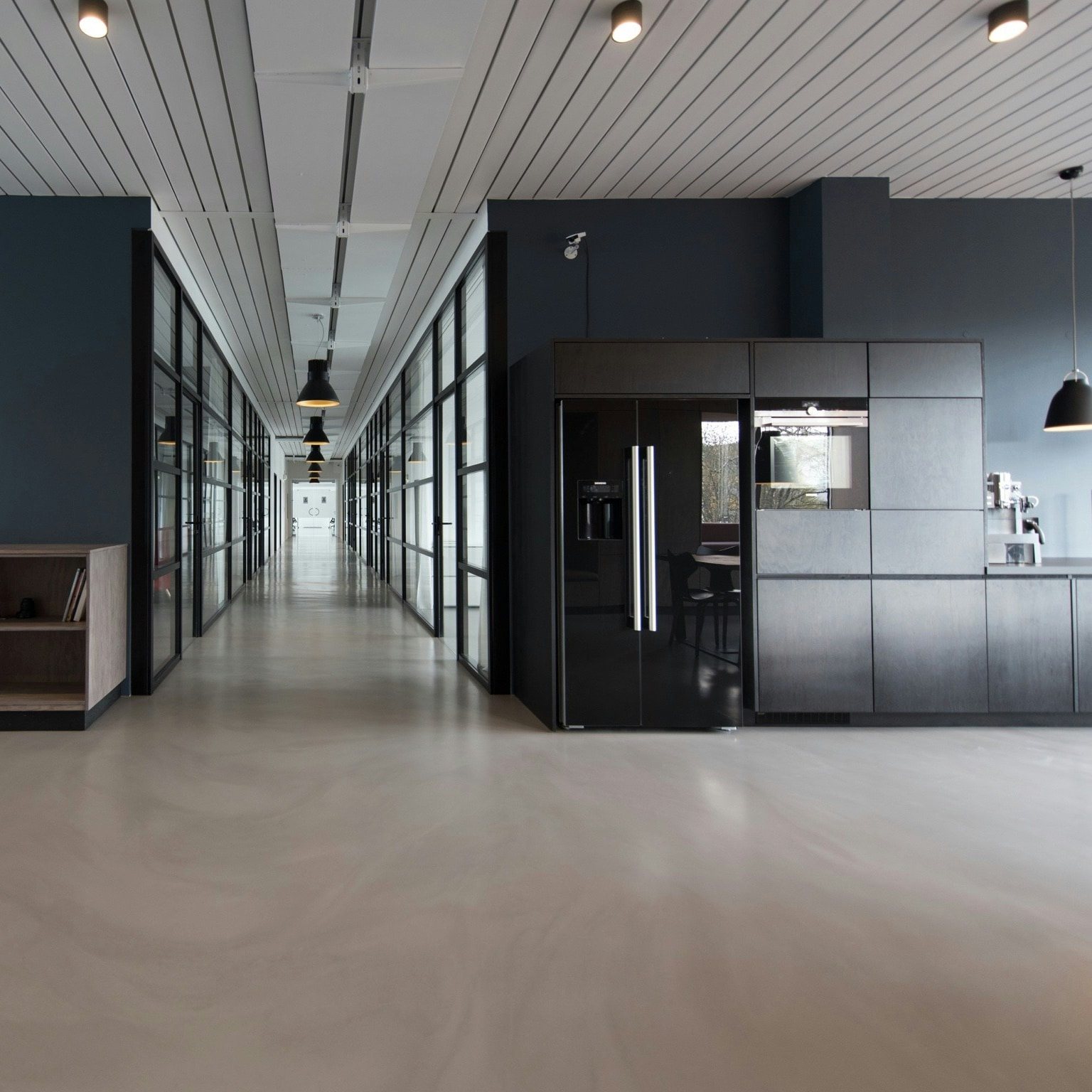 Open office floor with dark accent walls and a break-area kitchenette