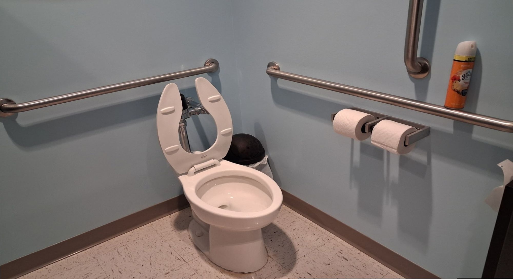 Accessible restroom stall with grab bars wiped down and floor mopped