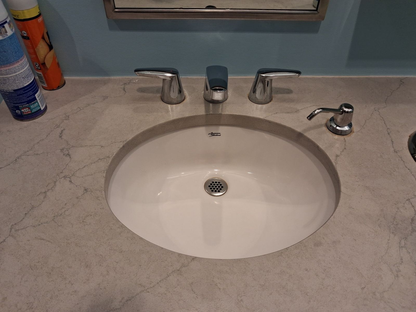 Restroom basin and tap wiped clean with the soap dispenser stocked beside it