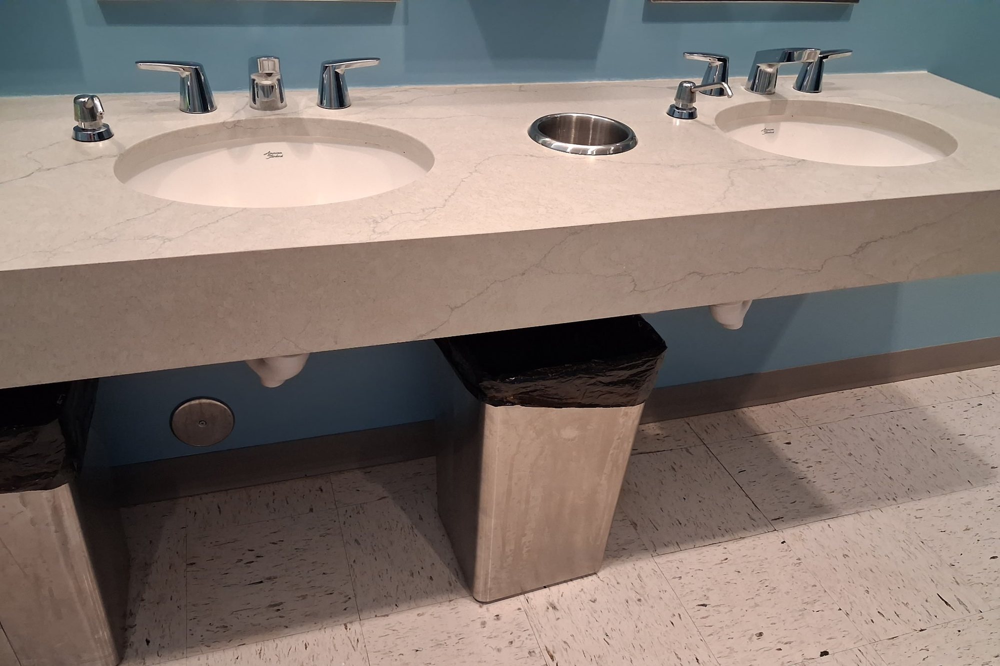Commercial restroom double vanity with two basins set in a stone counter